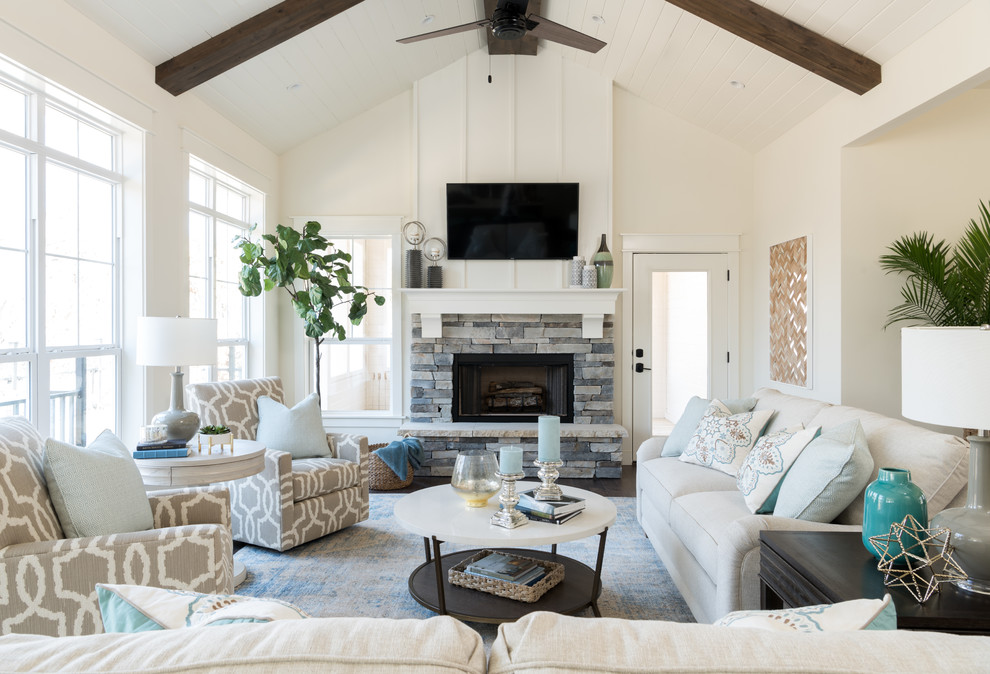 This is an example of a mid-sized beach style living room with white walls, a standard fireplace, a stone fireplace surround, a wall-mounted tv and dark hardwood floors.