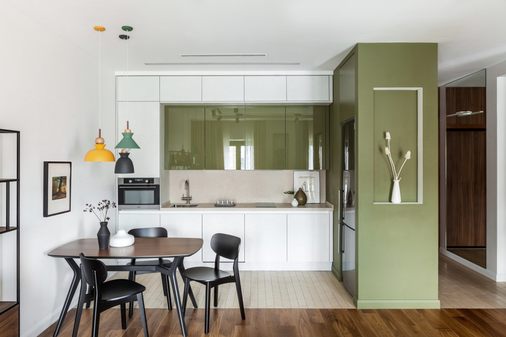 This is an example of a small scandinavian l-shaped eat-in kitchen in Moscow with an undermount sink, flat-panel cabinets, solid surface benchtops, beige splashback, stainless steel appliances, porcelain floors, no island, beige floor, beige benchtop and green cabinets.