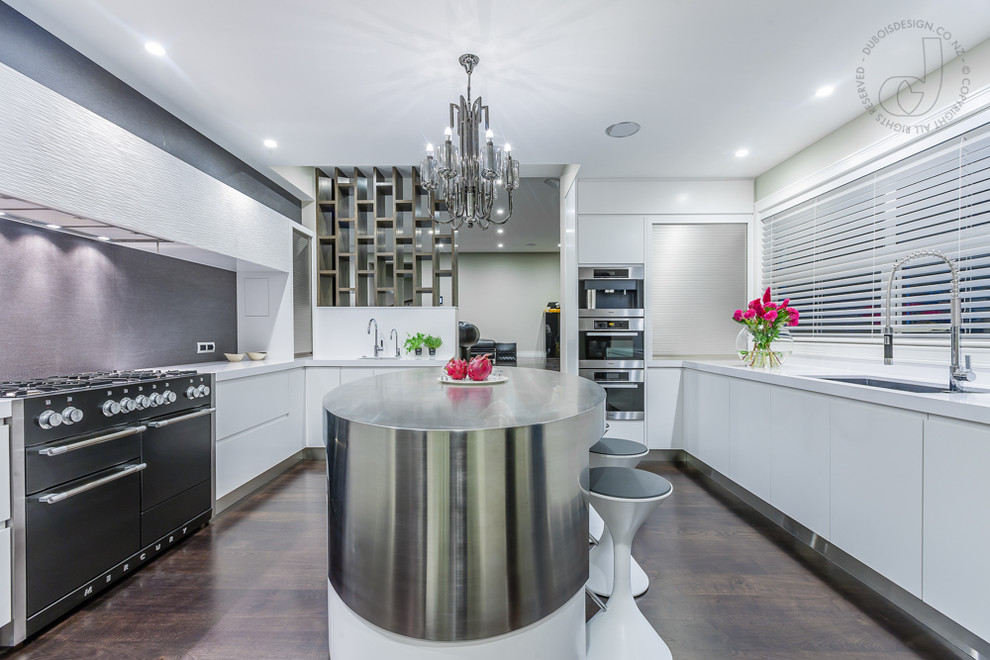 Photo of a Large modern U-shaped open plan kitchen in Auckland With Flat-panel Cabinets, White Cabinets, Quartz Benchtops, Black Splashback, Porcelain Splashback, Black Appliances, Dark Hardwood Floors, with Island and an Undermount Sink.