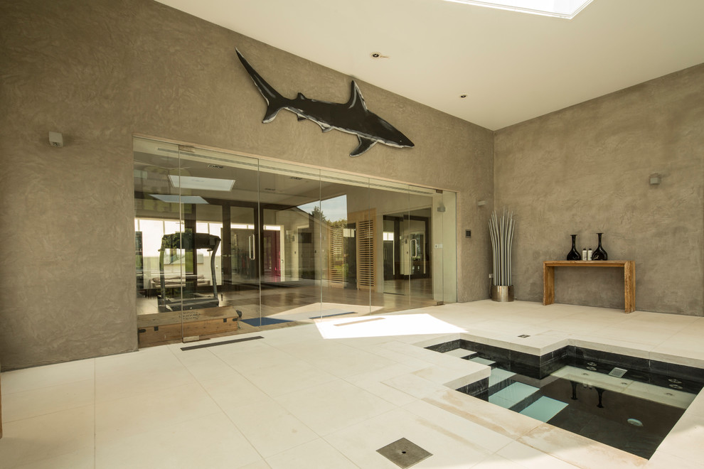 Design ideas for a large modern indoor rectangular lap pool in Hampshire with a hot tub and natural stone pavers.