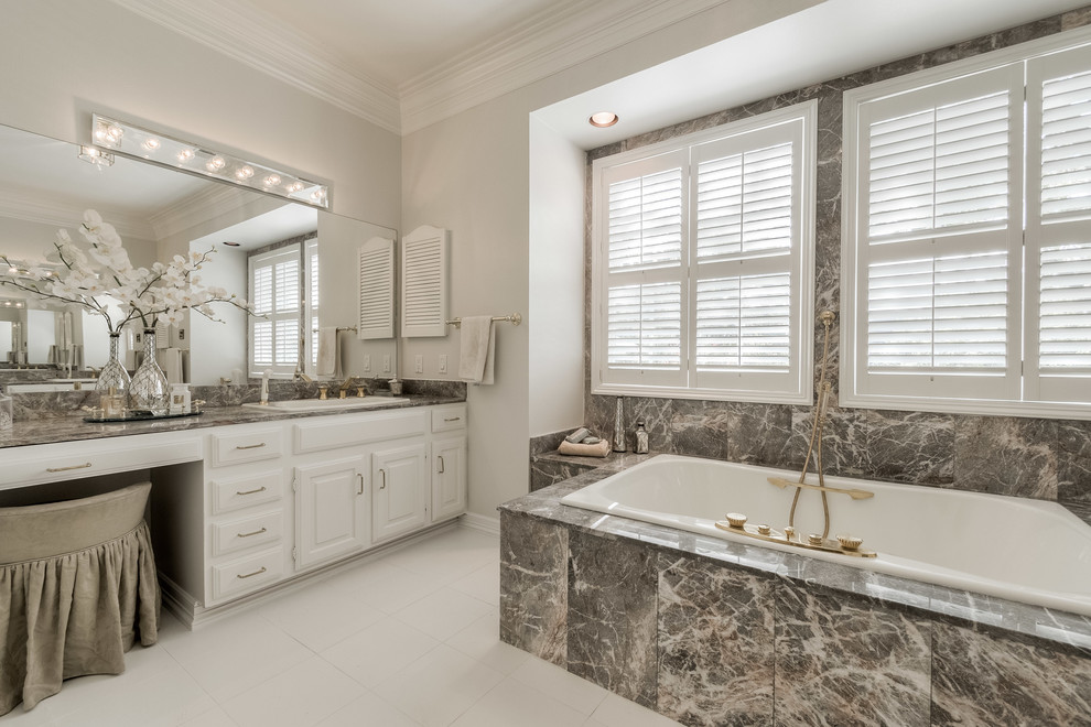 Design ideas for a traditional bathroom in Dallas with raised-panel cabinets, white cabinets, a drop-in tub, grey walls and a drop-in sink.