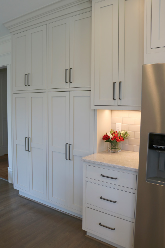 Inspiration for a large transitional galley medium tone wood floor and brown floor enclosed kitchen remodel with a farmhouse sink, shaker cabinets, gray cabinets, quartzite countertops, stainless steel appliances, beige backsplash, subway tile backsplash and a peninsula