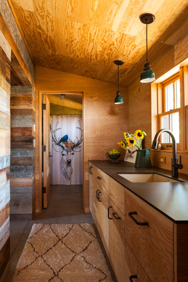 Inspiration for a mid-sized rustic galley concrete floor enclosed kitchen remodel with an undermount sink, flat-panel cabinets, medium tone wood cabinets, wood backsplash, no island, black countertops and quartz countertops