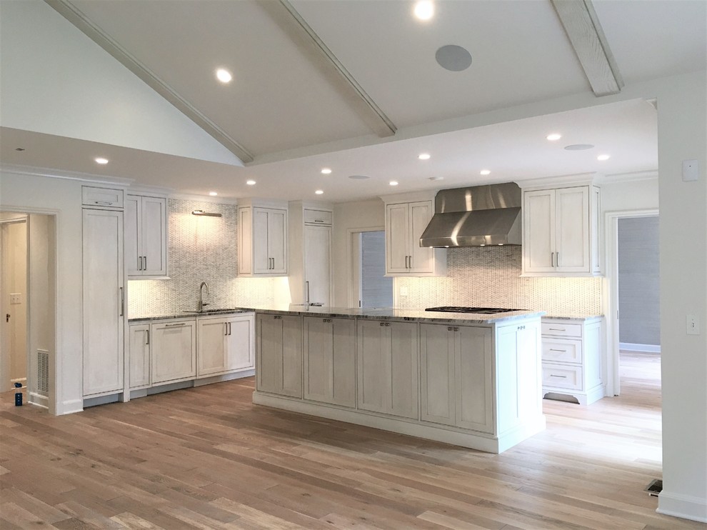 Example of a large transitional l-shaped medium tone wood floor and brown floor eat-in kitchen design with an undermount sink, flat-panel cabinets, gray cabinets, marble countertops, gray backsplash, marble backsplash, paneled appliances and an island