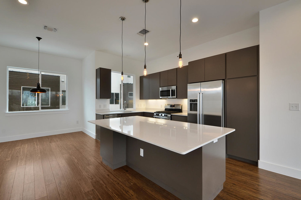 Photo of a mid-sized modern l-shaped eat-in kitchen in Austin with an undermount sink, flat-panel cabinets, brown cabinets, quartz benchtops, stainless steel appliances, bamboo floors and with island.