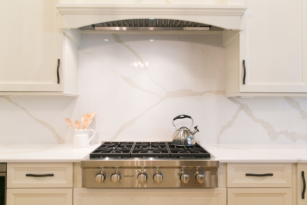 Inspiration for a mid-sized transitional u-shaped open concept kitchen remodel in Orlando with recessed-panel cabinets, white cabinets, quartzite countertops, white backsplash, stone slab backsplash, stainless steel appliances and a peninsula