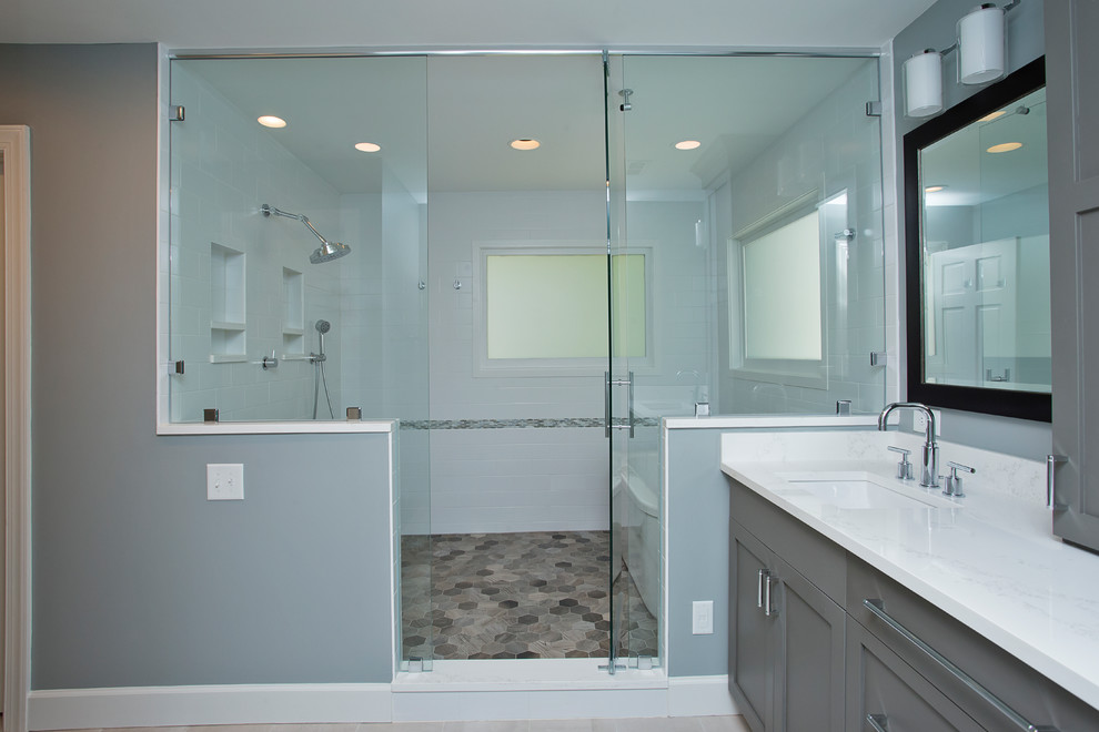 Design ideas for a large transitional master wet room bathroom in Raleigh with shaker cabinets, grey cabinets, a freestanding tub, a two-piece toilet, white tile, ceramic tile, blue walls, porcelain floors, an undermount sink, engineered quartz benchtops, grey floor, a hinged shower door and white benchtops.