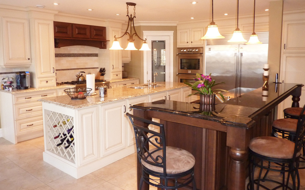 Example of a mid-sized transitional l-shaped ceramic tile and beige floor open concept kitchen design with an undermount sink, raised-panel cabinets, white cabinets, granite countertops, beige backsplash, ceramic backsplash, stainless steel appliances, two islands and beige countertops