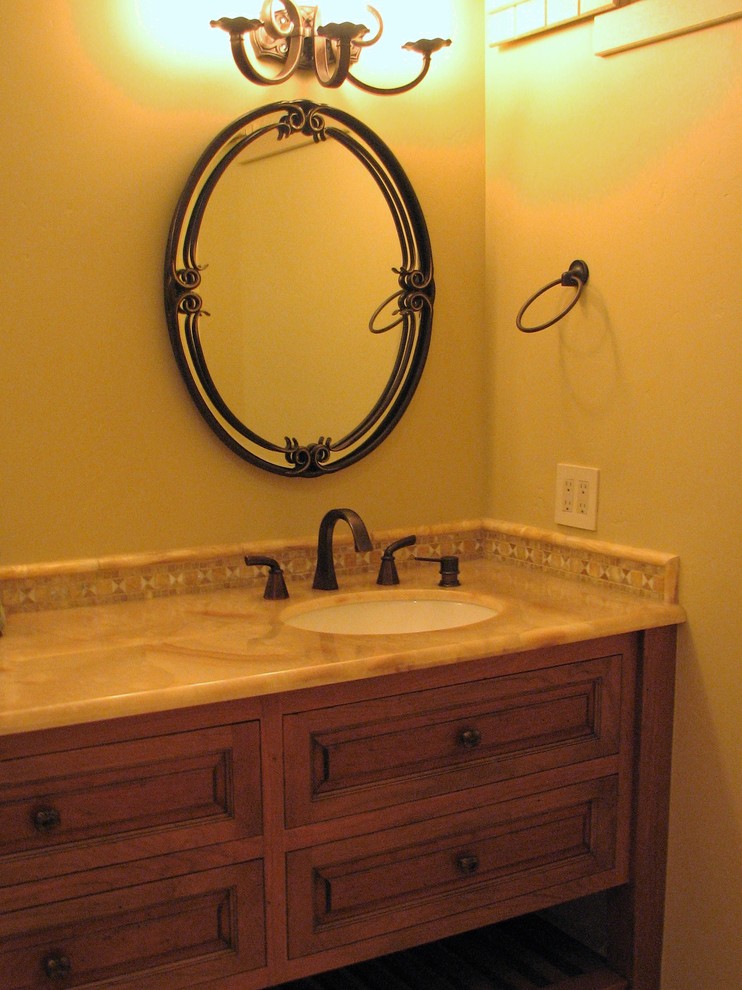 Inspiration for a mid-sized traditional 3/4 bathroom in Seattle with furniture-like cabinets, medium wood cabinets, an alcove shower, a one-piece toilet, yellow tile, mosaic tile, yellow walls, limestone floors, an undermount sink, onyx benchtops, yellow floor and a hinged shower door.
