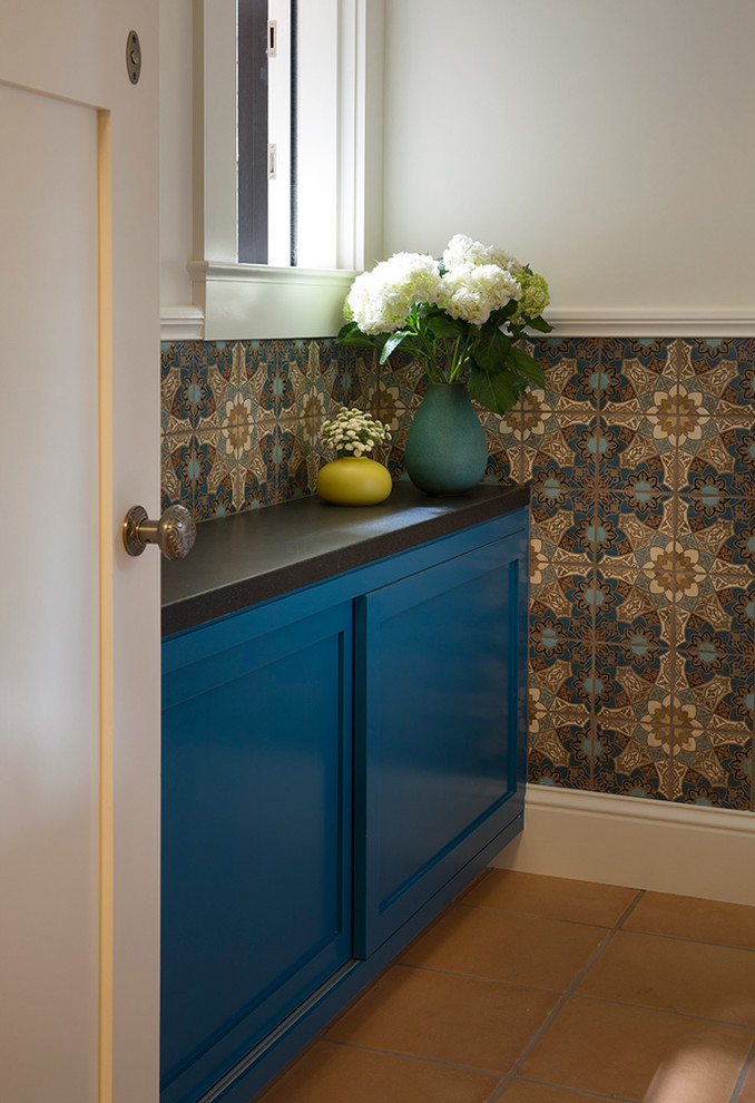 Inspiration for an eclectic bathroom in San Francisco with shaker cabinets, blue cabinets, multi-coloured tile, white walls, terra-cotta floors, a wall-mount sink and brown floor.