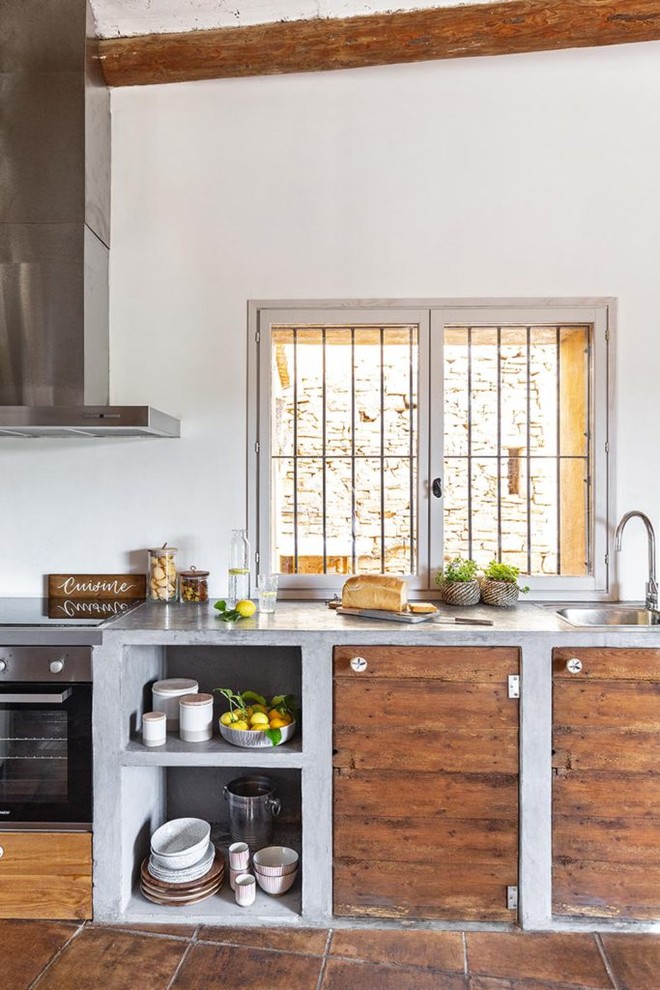 This is an example of a large mediterranean single-wall kitchen in Other with a drop-in sink, flat-panel cabinets, medium wood cabinets, concrete benchtops, white splashback, brown floor and grey benchtop.
