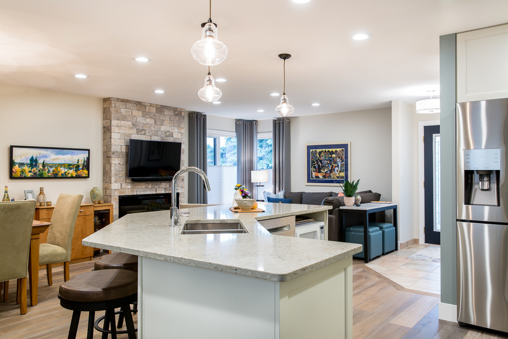 Eat-in kitchen - transitional l-shaped medium tone wood floor eat-in kitchen idea in Edmonton with an undermount sink, shaker cabinets, white cabinets, quartz countertops, white backsplash, porcelain backsplash, stainless steel appliances and an island