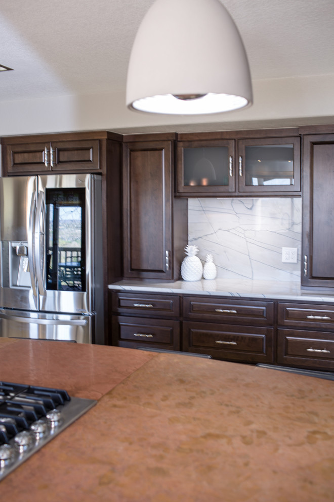 Photo of a large transitional u-shaped eat-in kitchen in Denver with an undermount sink, raised-panel cabinets, dark wood cabinets, quartzite benchtops, white splashback, stone slab splashback, stainless steel appliances, travertine floors, with island, beige floor and white benchtop.