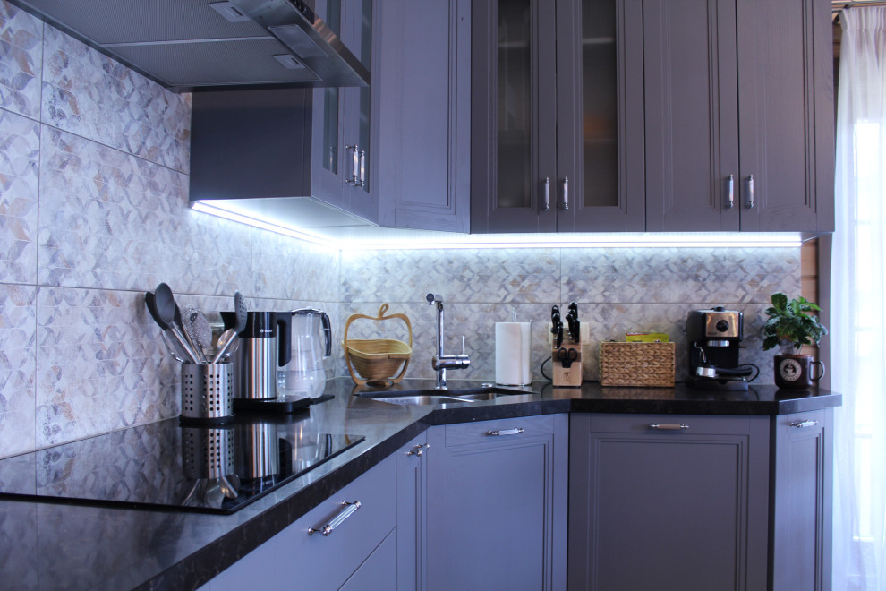 Foto di una cucina bohémian di medie dimensioni con lavello sottopiano, ante con riquadro incassato, ante grigie, top in granito, paraspruzzi grigio, elettrodomestici neri e top nero