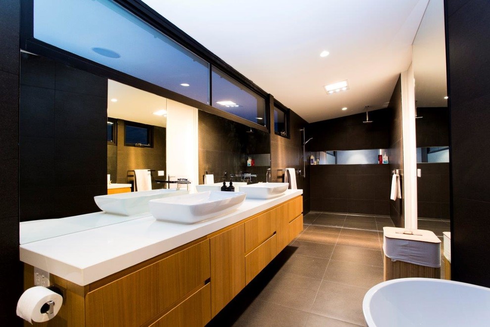 Inspiration for a mid-sized contemporary 3/4 bathroom in Melbourne with a drop-in sink, medium wood cabinets, a freestanding tub, an open shower, a bidet, gray tile, porcelain tile, brown walls, porcelain floors and an open shower.