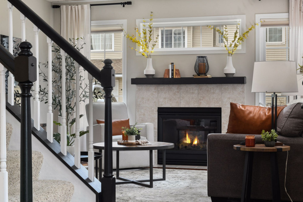 На фото: маленькая гостиная комната в стиле неоклассика (современная классика) с серыми стенами, полом из ламината, стандартным камином, фасадом камина из плитки и коричневым полом для на участке и в саду с