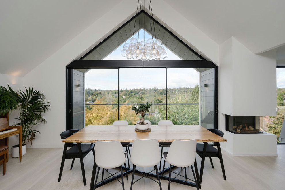This is an example of a large contemporary open plan dining in Surrey with white walls, light hardwood floors and vaulted.