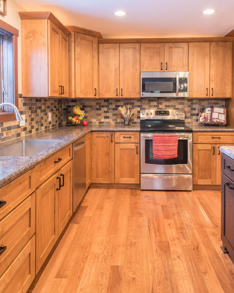 Photo of a large arts and crafts l-shaped eat-in kitchen in Minneapolis with an undermount sink, shaker cabinets, medium wood cabinets, laminate benchtops, multi-coloured splashback, mosaic tile splashback, stainless steel appliances, medium hardwood floors, with island, brown floor and turquoise benchtop.