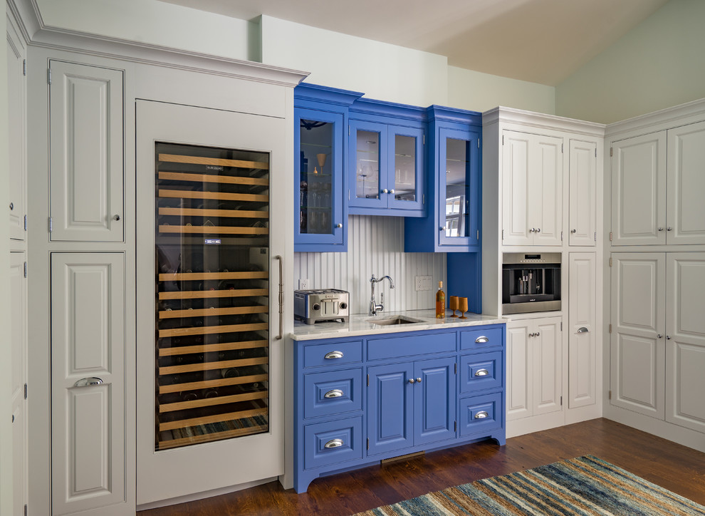 Design ideas for a traditional wet bar in Boston with an undermount sink, glass-front cabinets, blue cabinets, beige splashback, dark hardwood floors and beige benchtop.