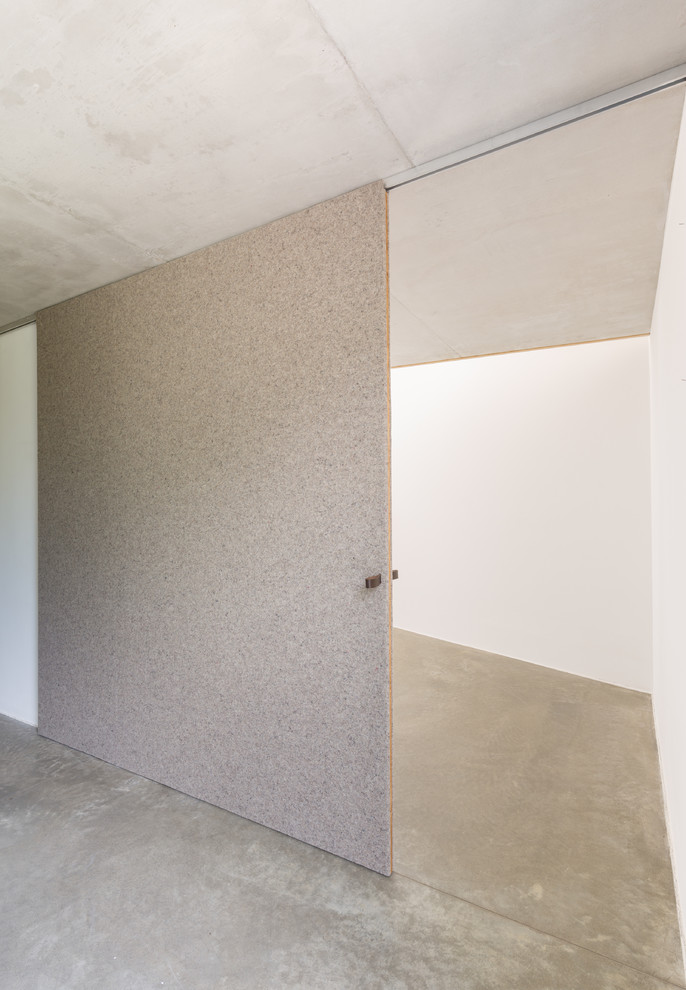 Mittelgroßes Modernes Schlafzimmer im Loft-Style mit weißer Wandfarbe, Betonboden und grauem Boden in Leipzig