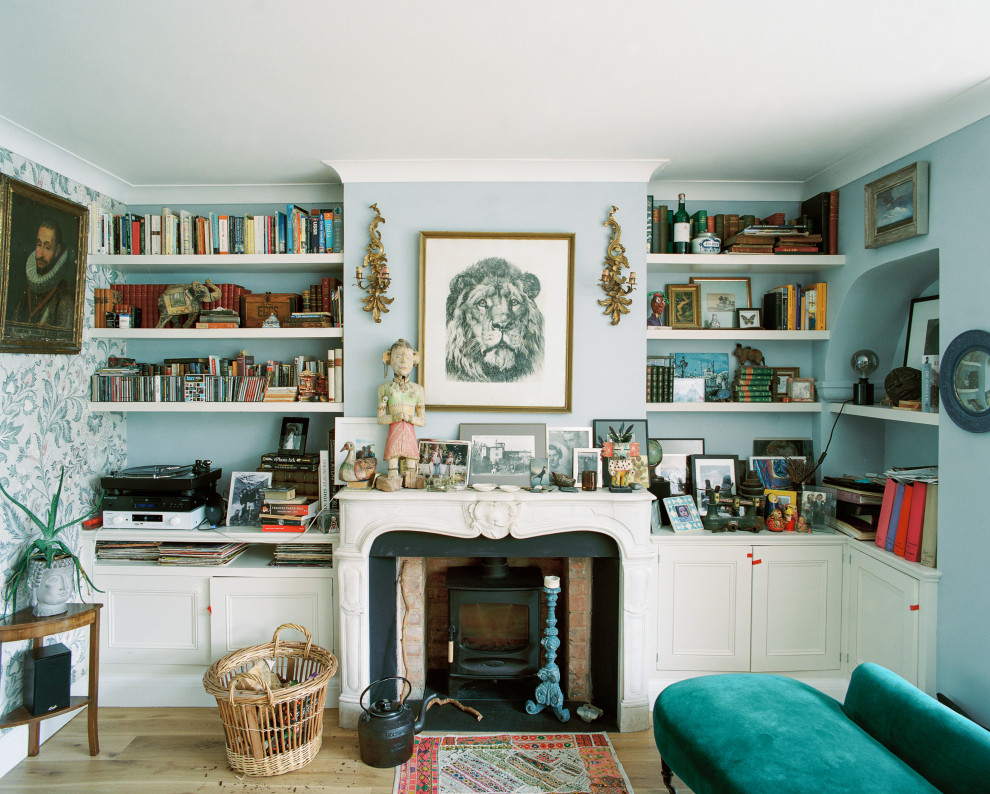 Cette photo montre une salle de séjour tendance de taille moyenne et ouverte avec une bibliothèque ou un coin lecture, un mur bleu, parquet clair, un poêle à bois, un manteau de cheminée en carrelage et aucun téléviseur.