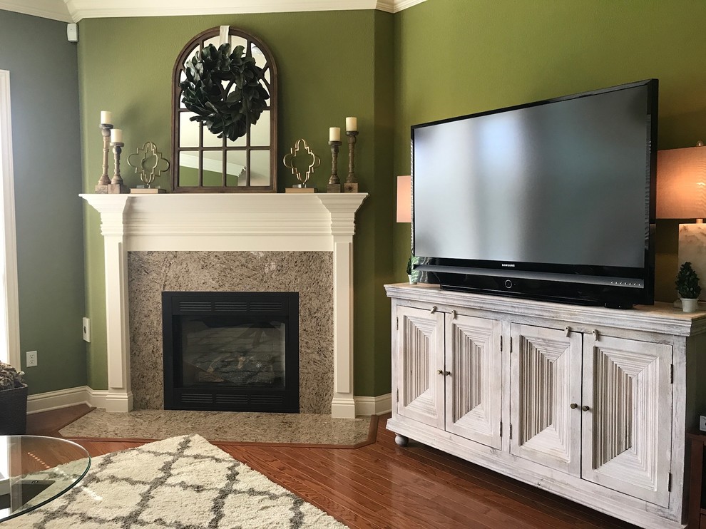 Inspiration for a mid-sized transitional open concept family room in Other with green walls, medium hardwood floors, a standard fireplace, a tile fireplace surround, a freestanding tv and brown floor.