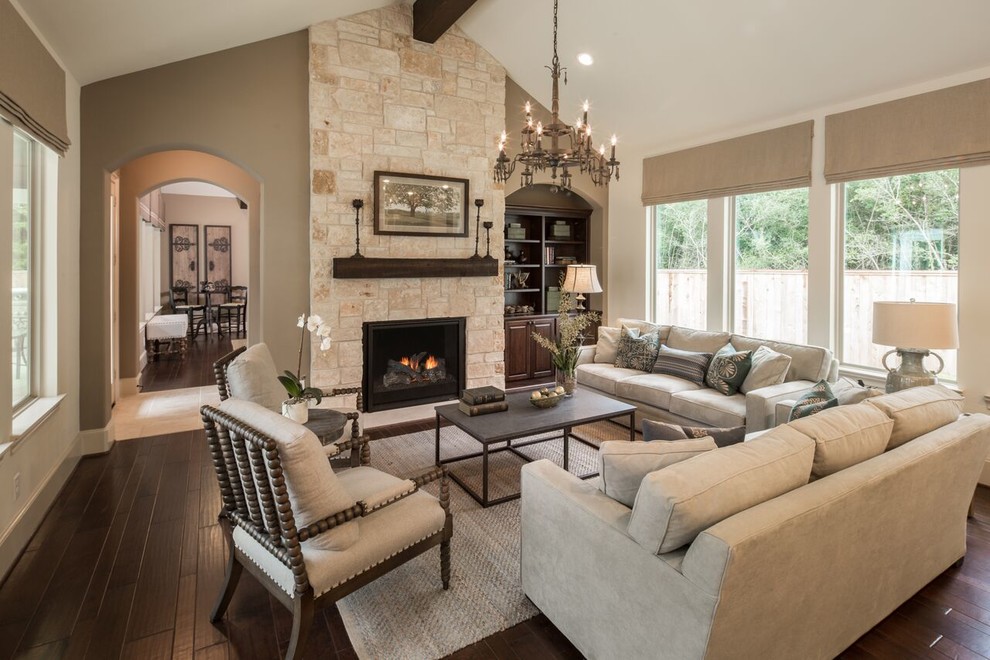 This is an example of a mediterranean enclosed living room in Houston with beige walls, dark hardwood floors, a standard fireplace, a stone fireplace surround, no tv and beige floor.
