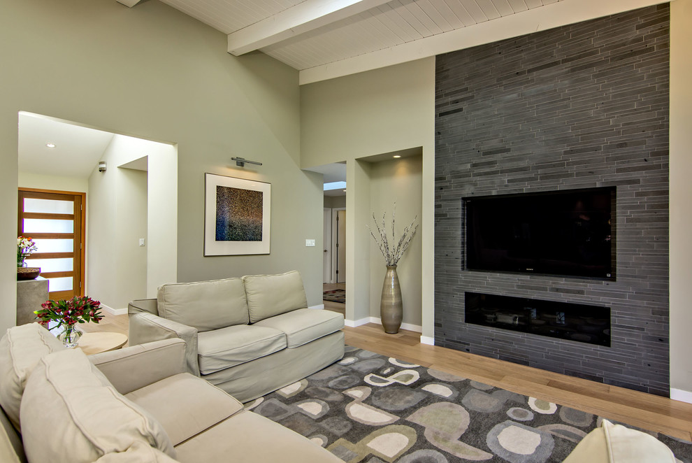 Photo of a large transitional open concept family room in San Francisco with beige walls, medium hardwood floors, a ribbon fireplace, a tile fireplace surround, a wall-mounted tv and brown floor.