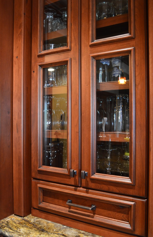 Photo of a large traditional l-shaped wet bar in Denver with glass-front cabinets and medium wood cabinets.