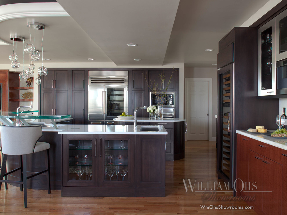 Inspiration for a transitional l-shaped eat-in kitchen remodel in Denver with a drop-in sink, beaded inset cabinets, brown cabinets, quartz countertops, glass sheet backsplash and stainless steel appliances