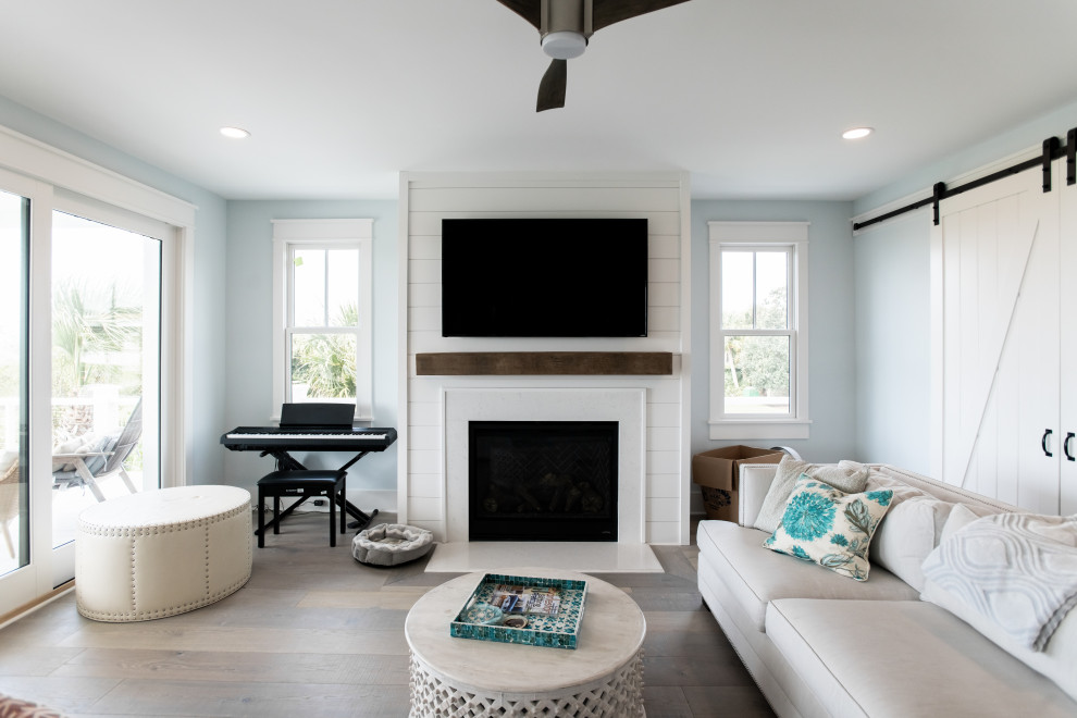 Inspiration for a large coastal open concept medium tone wood floor living room remodel in Charleston with blue walls, a standard fireplace, a shiplap fireplace and a wall-mounted tv