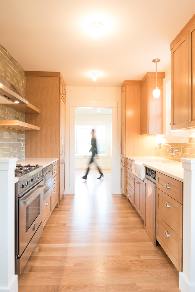 This is an example of a small arts and crafts galley eat-in kitchen in Portland with a farmhouse sink, shaker cabinets, medium wood cabinets, quartz benchtops, green splashback, ceramic splashback, stainless steel appliances and medium hardwood floors.