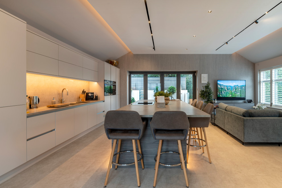 Inspiration for a large contemporary galley open plan kitchen in Cheshire with an undermount sink, flat-panel cabinets, beige cabinets, beige splashback, stainless steel appliances, porcelain floors, with island, grey floor and grey benchtop.