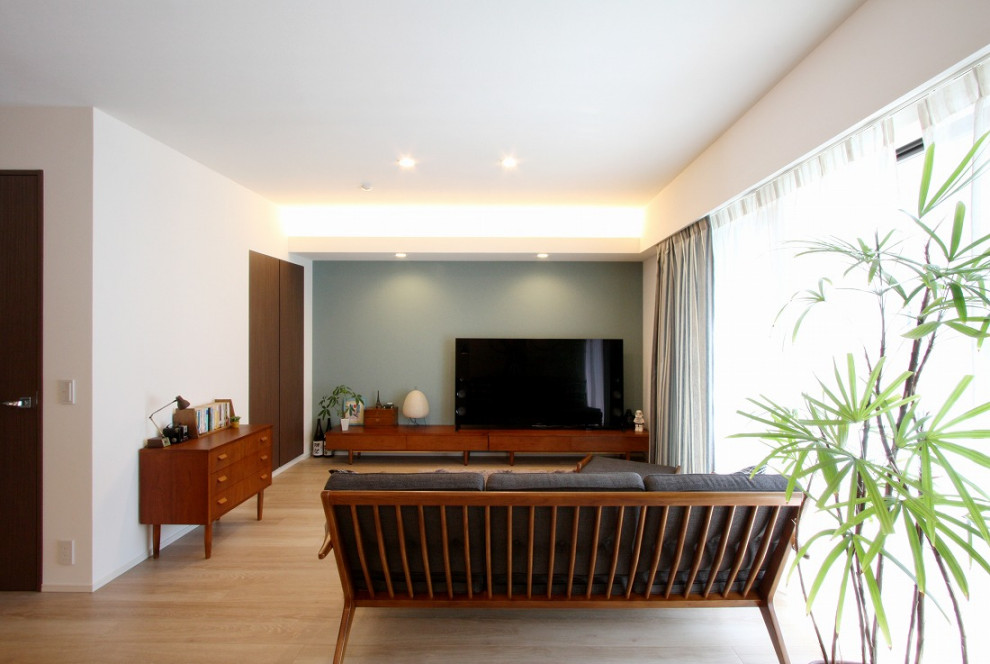 Источник вдохновения для домашнего уюта: открытая гостиная комната среднего размера в стиле модернизм с зелеными стенами, светлым паркетным полом, отдельно стоящим телевизором, бежевым полом, потолком с обоями, обоями на стенах и синим диваном