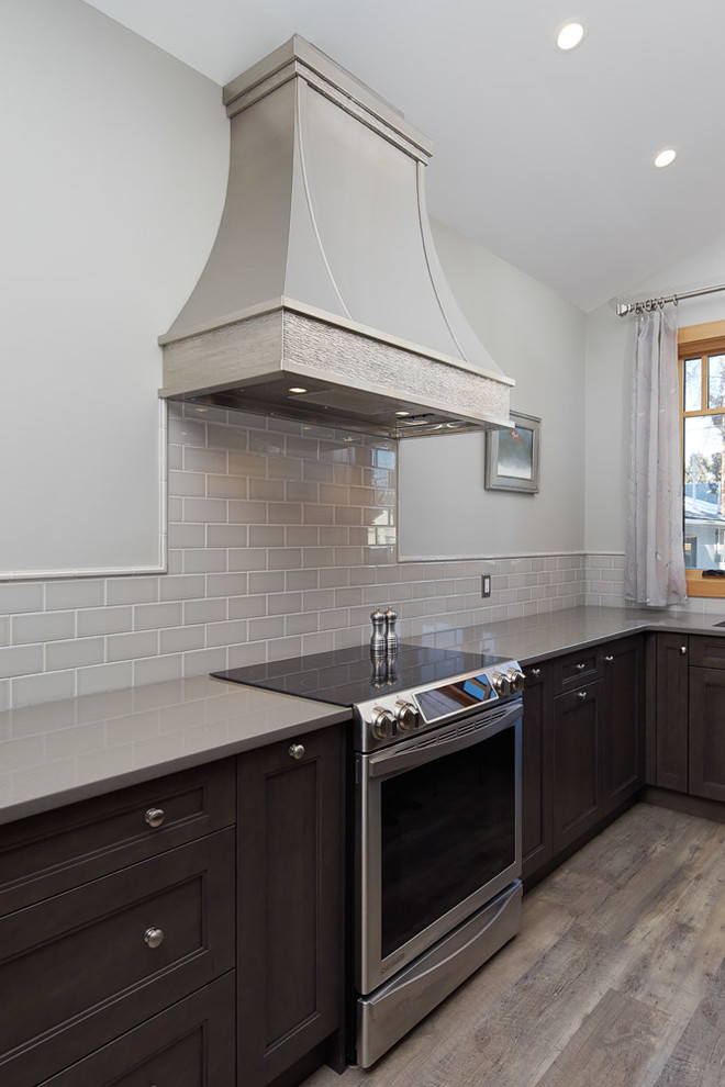 Example of a small transitional u-shaped medium tone wood floor and gray floor open concept kitchen design in Calgary with an undermount sink, recessed-panel cabinets, dark wood cabinets, quartz countertops, gray backsplash, subway tile backsplash, stainless steel appliances and a peninsula