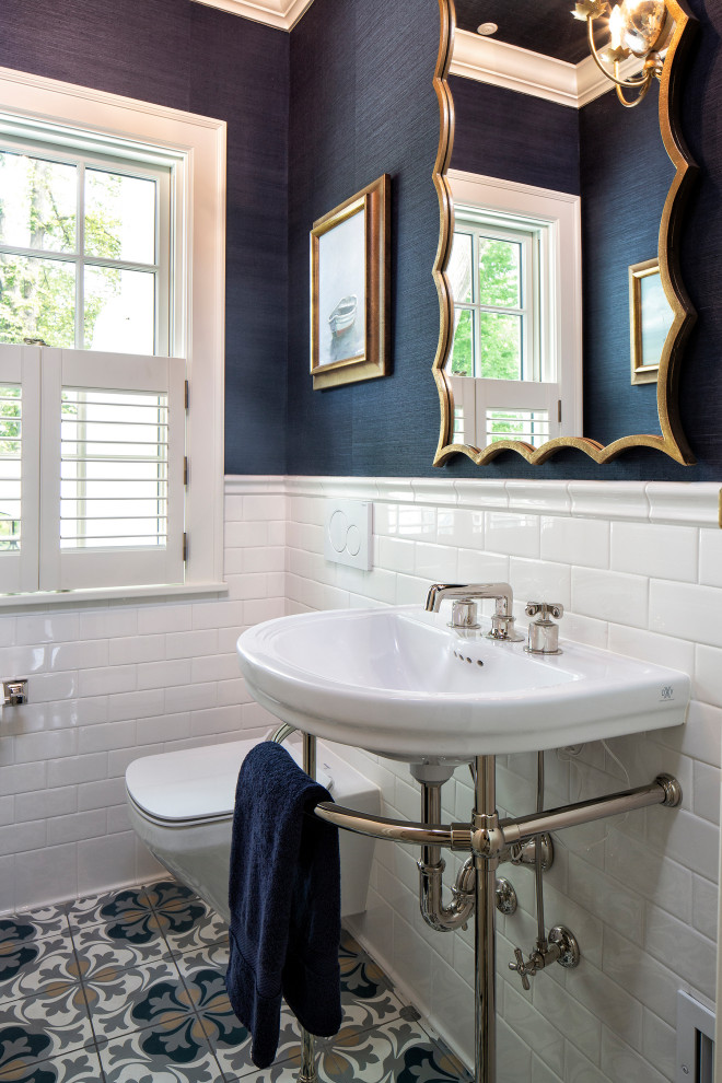 Photo of a small mediterranean powder room in Minneapolis with a wall-mount toilet, white tile, ceramic tile, blue walls, ceramic floors, a console sink, blue floor, a freestanding vanity, wallpaper and wallpaper.