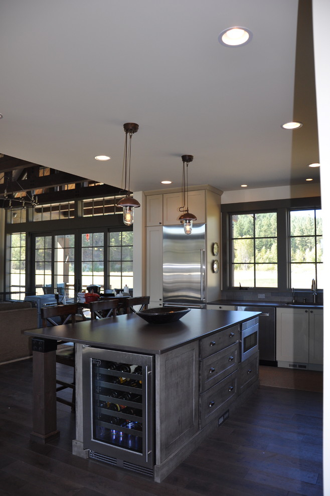 Inspiration for a large rustic l-shaped medium tone wood floor eat-in kitchen remodel in Seattle with an undermount sink, shaker cabinets, distressed cabinets, quartz countertops, gray backsplash, stone tile backsplash, stainless steel appliances and an island