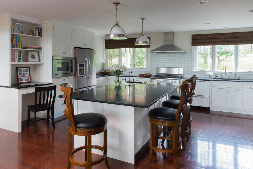 Kitchen - large transitional u-shaped medium tone wood floor kitchen idea with an undermount sink, recessed-panel cabinets, white cabinets, granite countertops, blue backsplash, glass tile backsplash, stainless steel appliances, an island and black countertops