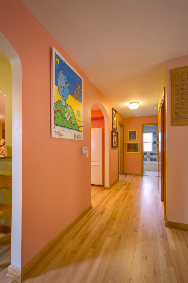 Modern hallway in Milwaukee with pink walls and light hardwood floors.