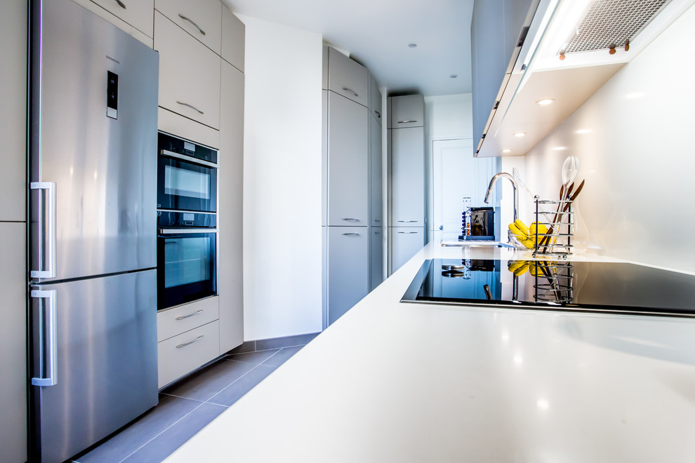 Design ideas for a mid-sized contemporary galley separate kitchen in Paris with an integrated sink, beaded inset cabinets, white cabinets, quartzite benchtops, white splashback, stainless steel appliances, ceramic floors, no island and grey floor.