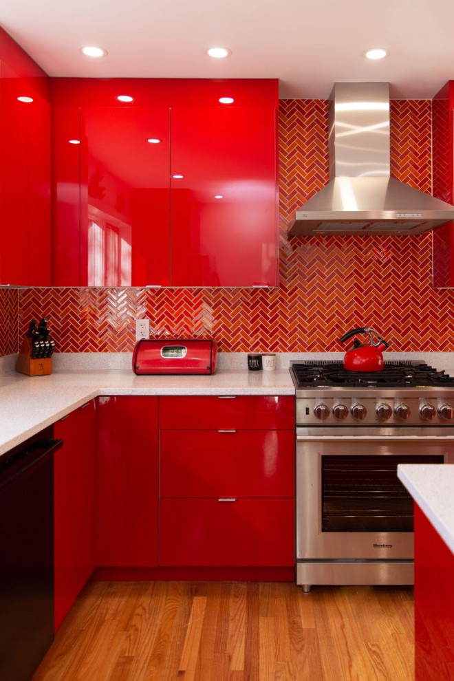 This is an example of a mid-sized eclectic l-shaped eat-in kitchen in New York with an undermount sink, flat-panel cabinets, red cabinets, quartz benchtops, multi-coloured splashback, ceramic splashback, stainless steel appliances, light hardwood floors, with island, brown floor and white benchtop.