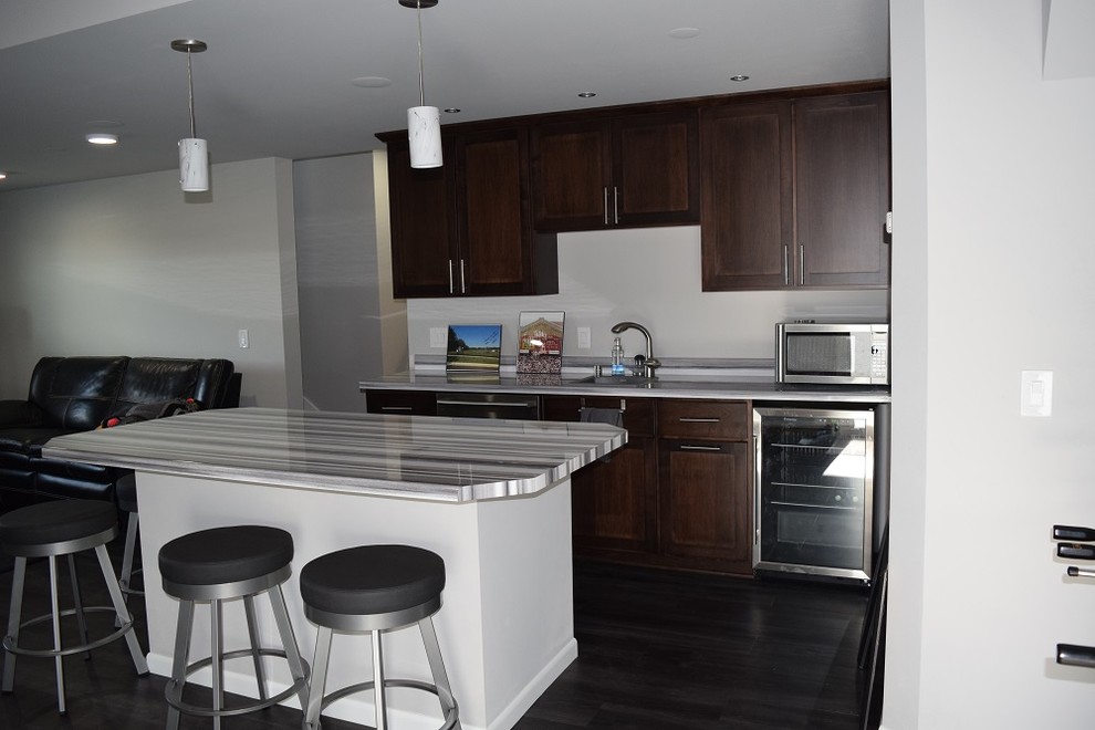 Example of a large transitional enclosed and single-wall vinyl floor open concept kitchen design with white walls, no fireplace, no tv, an undermount sink, shaker cabinets, dark wood cabinets, quartzite countertops and an island