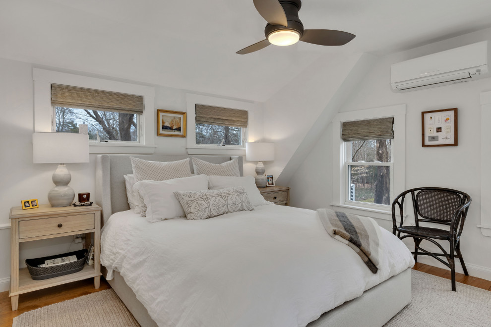 Ejemplo de dormitorio principal costero de tamaño medio con paredes blancas, suelo de madera clara y suelo marrón
