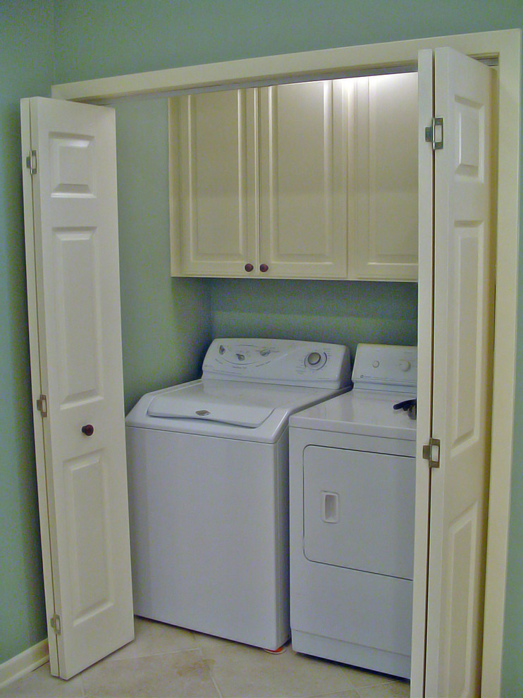 Large traditional laundry cupboard in New Orleans with white cabinets, blue walls and a side-by-side washer and dryer.