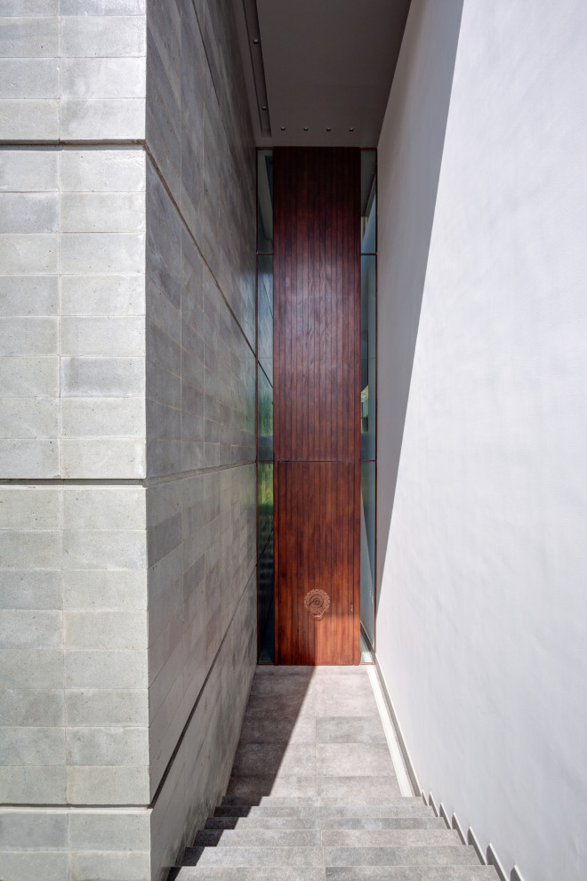 На фото: большая входная дверь в современном стиле с серыми стенами, полом из сланца, поворотной входной дверью, входной дверью из дерева среднего тона и серым полом
