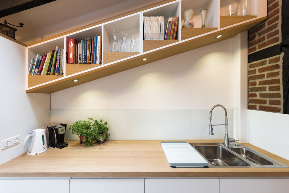 Geschlossene, Einzeilige, Mittelgroße Moderne Küche ohne Insel mit Einbauwaschbecken, Kassettenfronten, weißen Schränken, Arbeitsplatte aus Holz, Küchenrückwand in Weiß, Glasrückwand, weißen Elektrogeräten, hellem Holzboden, beigem Boden und beiger Arbeitsplatte in Sonstige