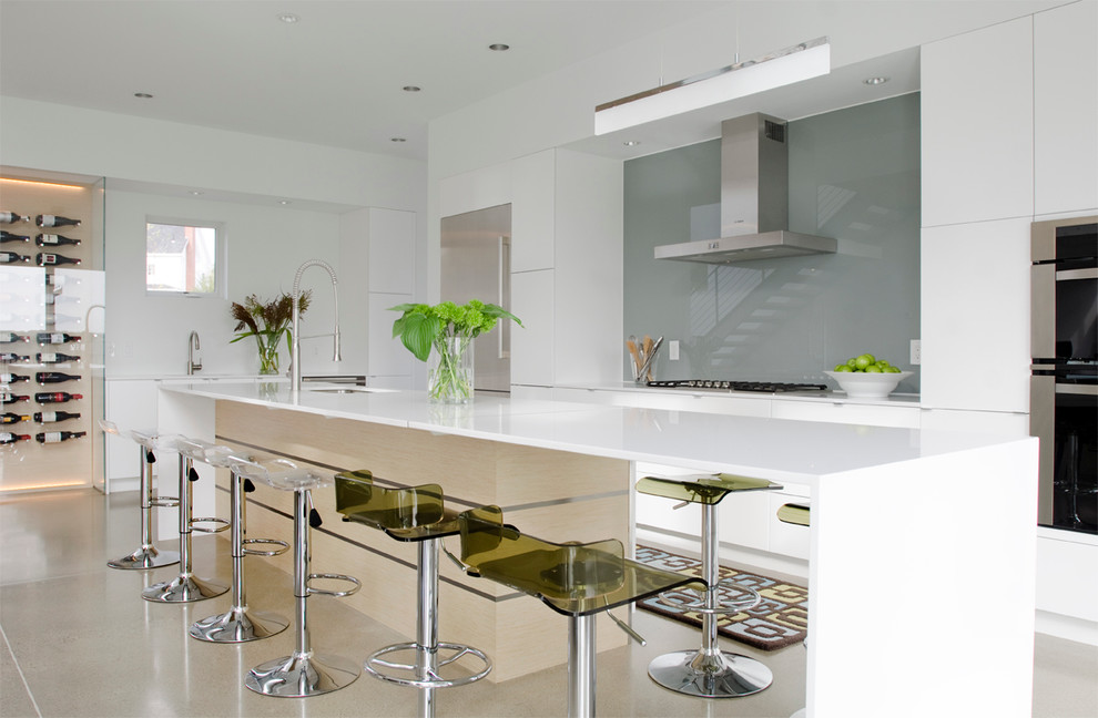 Inspiration for a contemporary open plan kitchen in Portland Maine with flat-panel cabinets, white cabinets, grey splashback, glass sheet splashback, stainless steel appliances and with island.