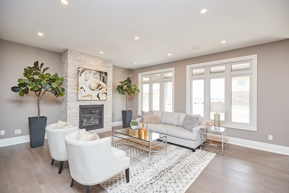 Inspiration for a mid-sized transitional open concept living room in Other with a music area, grey walls, medium hardwood floors, a standard fireplace, a stone fireplace surround, a wall-mounted tv and grey floor.