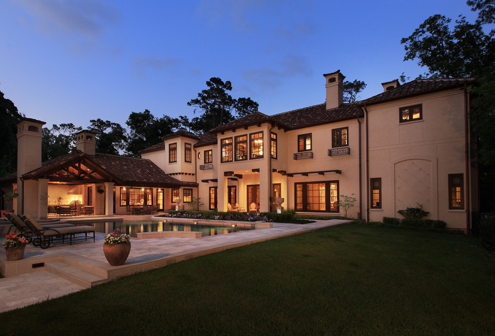 Design ideas for an expansive mediterranean two-storey beige exterior in Houston with stone veneer and a hip roof.