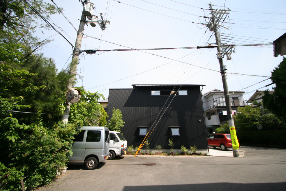 Inspiration pour une petite façade de maison métallique et noire asiatique en planches et couvre-joints à un étage avec un toit à deux pans, un toit en métal et un toit gris.